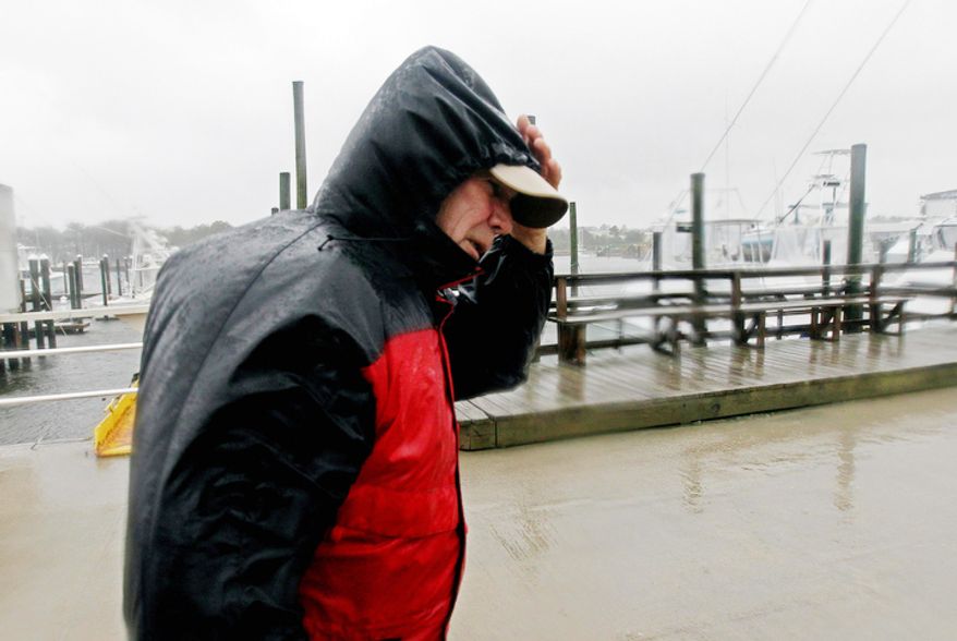 Skip Horney shields himself from the blowing rain after helping secure boats at Broad Creek Marina in Wanchese, N.C., Sunday, Oct. 28, 2012, as Hurricane Sandy moves up the East Coast. (AP Photo/Gerry Broome)