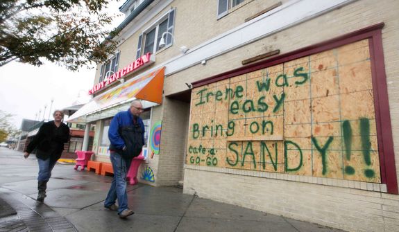 Residents still hang around the Rehoboth boardwalk as businesses board up their windows in preparation for the approaching Hurricane Sandy. (AP Photo/The News Journal, Suchat Pederson)
