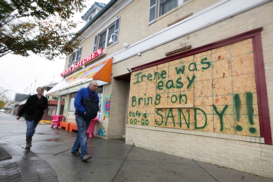 Residents still hang around the Rehoboth boardwalk as businesses board up their windows in preparation for the approaching Hurricane Sandy. (AP Photo/The News Journal, Suchat Pederson)