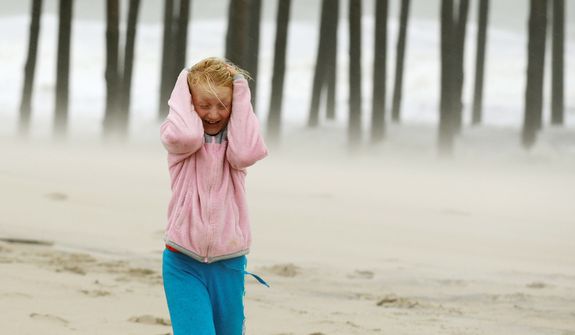 Molly White, 9, from Frankford, Del., covers her head as she is pelted by blowing sand on the beach, as Hurricane Sandy bears down on the East Coast in Ocean City, Md. (AP Photo/Alex Brandon)