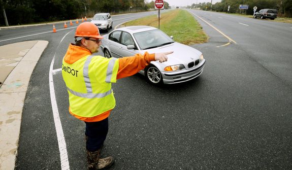 A worker with the Delaware Department of Transportation directs traffic off of Highway 1 at Fred Hudson Road as Hurricane Sandy bears down on the East Coast, Sunday, Oct. 28, 2012, in Bethany Beach, Del. Highway 1 is closed northbound from this point with water over the road according to the Delaware State Police. (AP Photo/Alex Brandon)