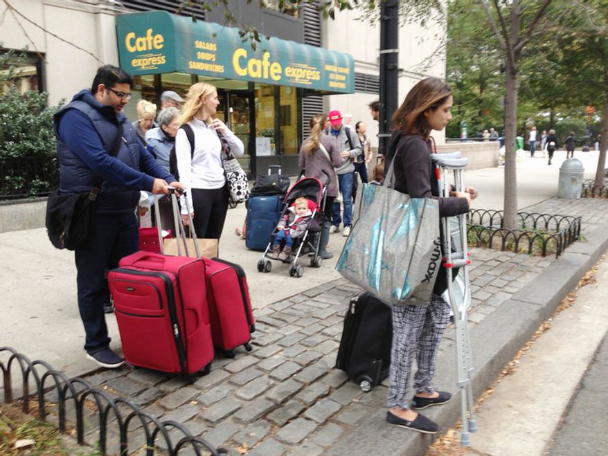 People line up looking for taxis, as they leave Battery Park City in lower Manhattan where a mandatory evacuation order is in place as Hurricane Sandy approaches the Northeast, in New York. (AP Photo/Santiago Lyon)