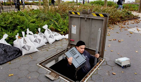 A technician with the Battery Conservancy removes below-ground fountain operation equipment near the water&#39;s edge at Battery Park in New York. Areas in the Northeast are preparing for the arrival of Hurricane Sandy and a possible flooding storm surge. (AP Photo/Craig Ruttle)
