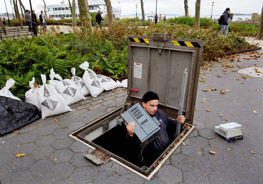 A technician with the Battery Conservancy removes below-ground fountain operation equipment near the water's edge at Battery Park in New York. Areas in the Northeast are preparing for the arrival of Hurricane Sandy and a possible flooding storm surge. (AP Photo/Craig Ruttle)