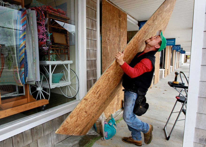 Jeremy Seidel, of Waterford, Conn., covers storefront windows with plywood in the Watch Hill section of Westerly, R.I., Sunday, Oct. 28, 2012, in preparation for high winds from the expected arrival of Hurricane Sandy. (AP Photo/Steven Senne)