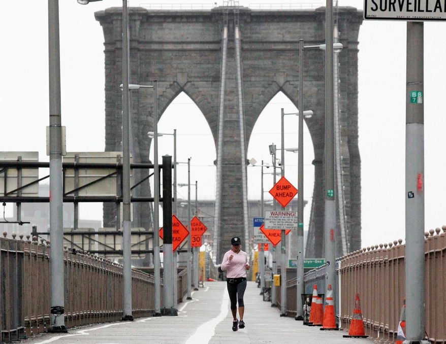 ** In this Oct. 29, 2012, file photo, a woman jogs across the Brooklyn Bridge in New York City. Many city residents were defiant as Hurricane Sandy moved toward the region, going about their daily routines in an attempt to maintain normalcy despite the worsening conditions. (Associated Press)