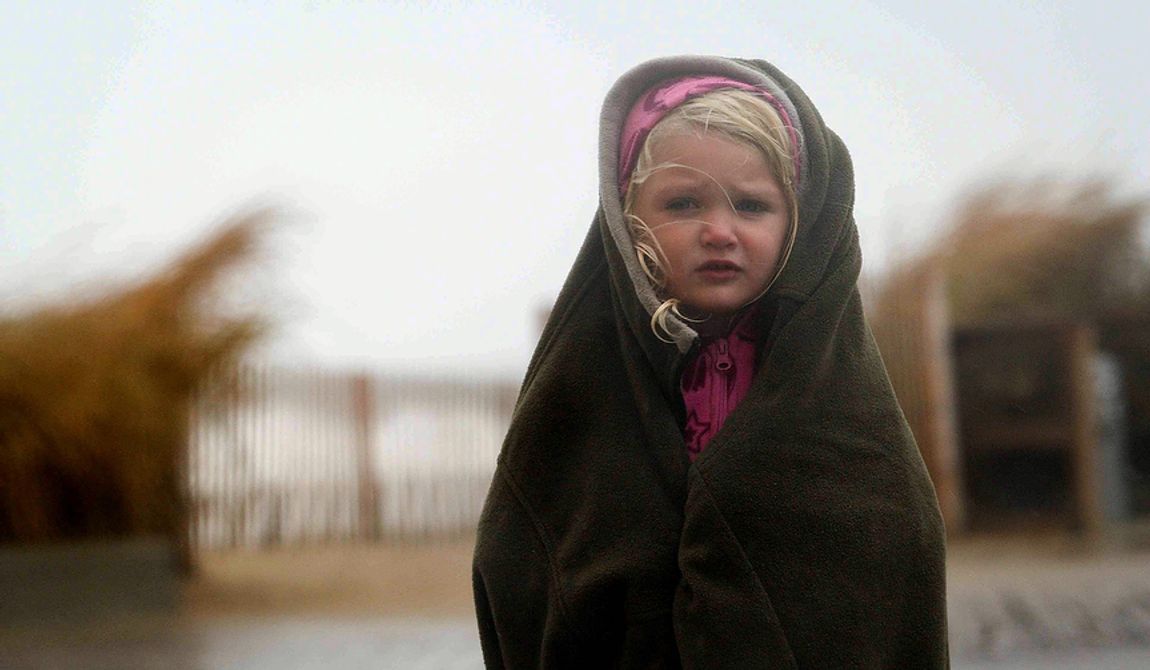Matison Cos, 3, tries to stay warm and dry along the boardwalk as her family comes to see the approaching Hurricane Sandy in Rehoboth Beach, Del., on Sunday, Oct. 28, 2012. (AP Photo/The News Journal, Suchat Pederson)