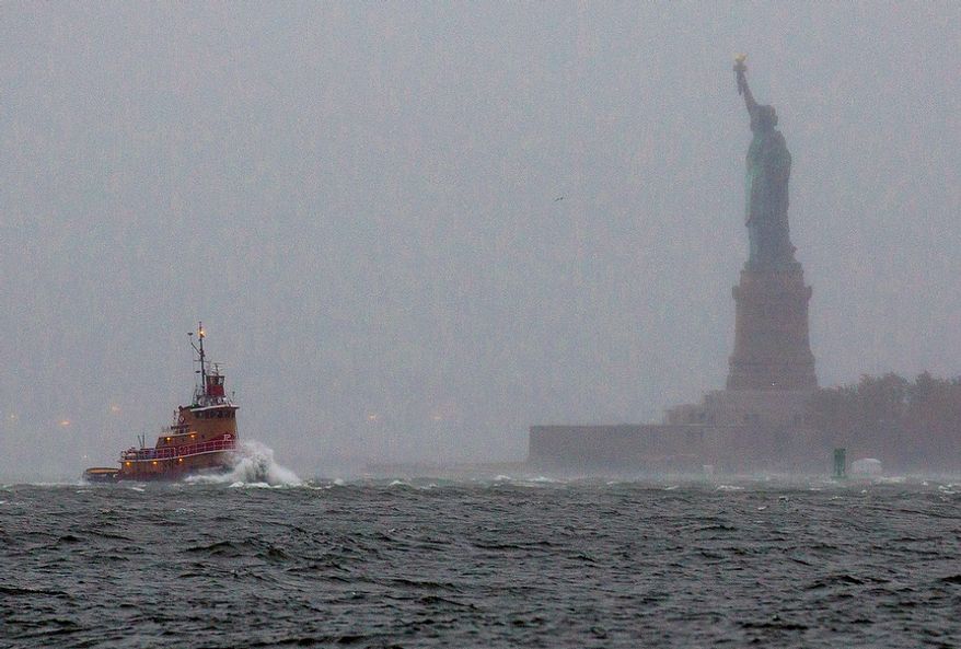 Waves crash over the bow of a tugboat as it passes near the Statue of Liberty in New York on Monday, Oct. 29, 2012, as rough water as the result of Hurricane Sandy churned the waters of New York Harbor. Hurricane Sandy continued on its path Monday, forcing the shutdown of mass transit, schools and financial markets; sending coastal residents fleeing; and threatening a dangerous mix of high winds and soaking rain. (AP Photo/Craig Ruttle)