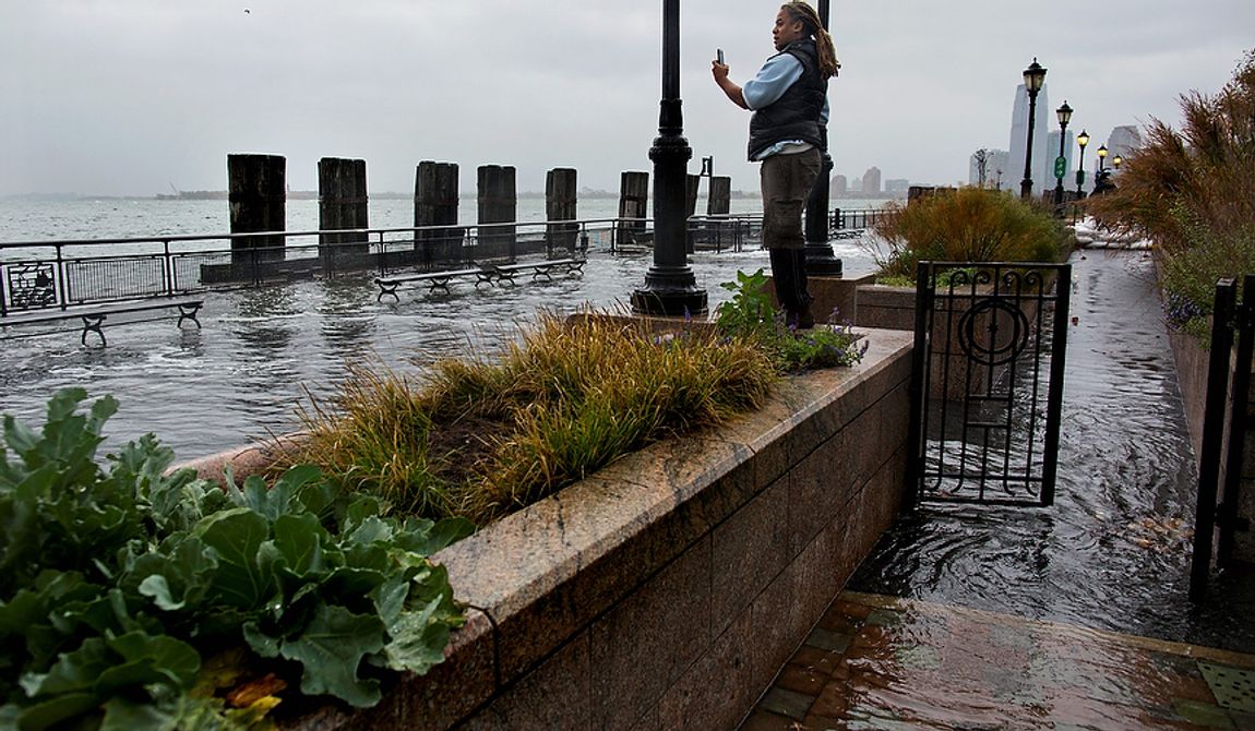Alix Brignol of New York takes a picture as water washes over the seawall near high tide at Battery Park in New York on Monday, Oct. 29, 2012, as Hurricane Sandy approaches the East Coast.Hurricane Sandy continued on its path Monday, forcing the shutdown of mass transit, schools and financial markets; sending coastal residents fleeing; and threatening a dangerous mix of high winds and soaking rain. (AP Photo/Craig Ruttle)