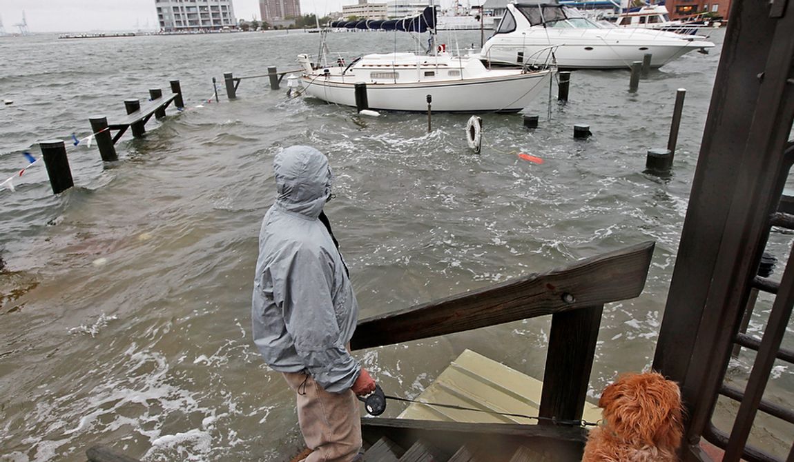 Jack Devnew and his dog check on his boat at a marina near downtown Norfolk, Va., on Monday, Oct. 29, 2012. Rain and wind from Hurricane Sandy were hitting the area. (AP Photo/Steve Helber)