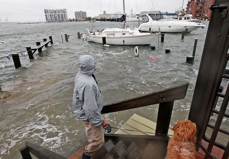 Jack Devnew and his dog check on his boat at a marina near downtown Norfolk, Va., on Monday, Oct. 29, 2012. Rain and wind from Hurricane Sandy were hitting the area. (AP Photo/Steve Helber)