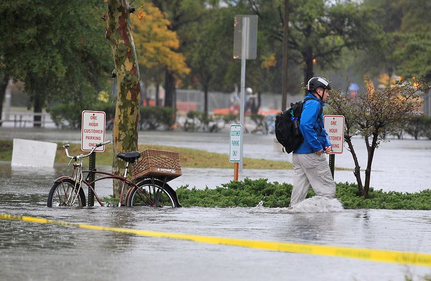 A Norfolk, Va., resident chains his bike and heads to work in floodwaters near downtown on Monday, Oct. 29, 2012. Rain and wind from Hurricane Sandy were hitting the area. (AP Photo/Steve Helber)