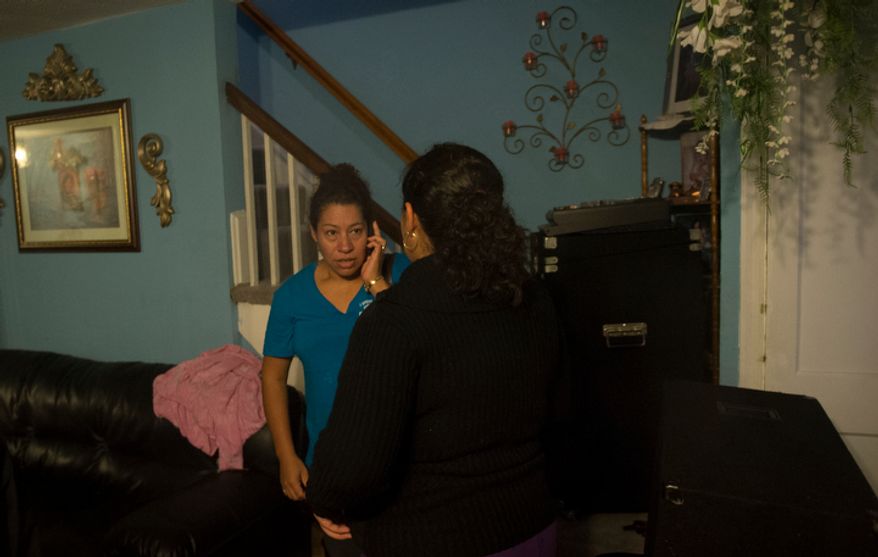 Rosa Merino uses her cell phone as she and her family leave their home on Arlington Terrace in the Huntington neighborhood of Alexandria, Va., on Oct. 29, 2012, during a mandatory evacuation order as high winds and heavy rain from Hurricane Sandy pound the Atlantic coast. (Rod Lamkey Jr./The Washington Times)