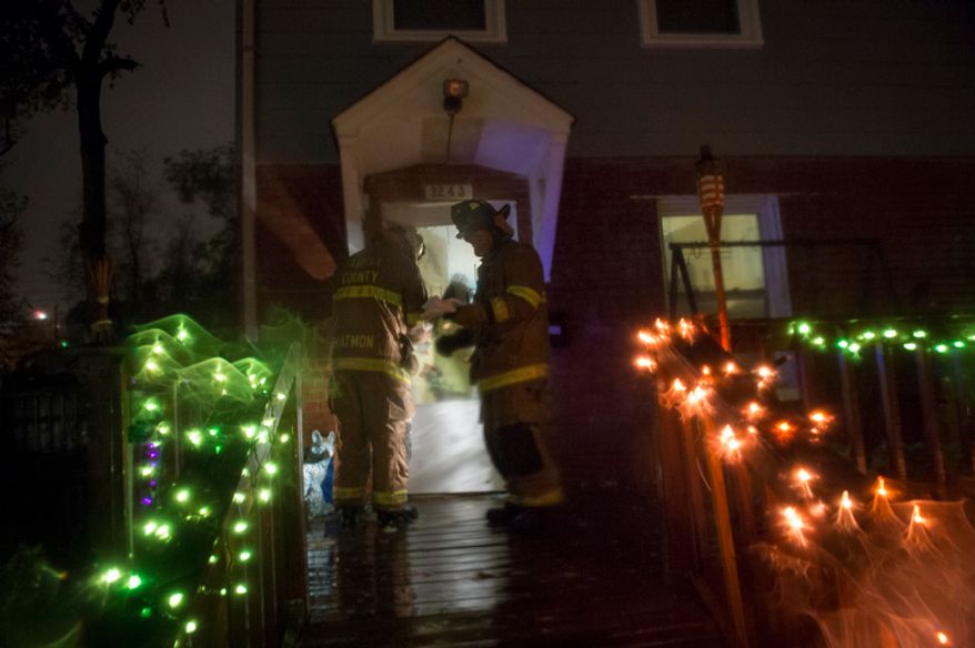 Fairfax County firefighters go door to door to check on residents on Arlington Terrace in the Huntington neighborhood of Alexandria, Va., on Oct. 29, 2012, during a mandatory evacuation order as high winds and heavy rain from Hurricane Sandy pound the Atlantic coast. (Rod Lamkey Jr./The Washington Times)