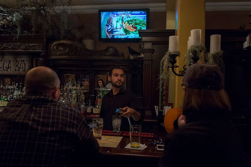 O'Connell's Restaurant server Mike Doran, of Waldorf, Md., takes care of customers as they watch the progress of Hurricane Sandy on the television in Old Town Alexandria, Va., Monday, Oct. 29, 2012, while Hurricane Sandy makes it's way north along the Atlantic coast. (Rod Lamkey Jr./The Washington Times)