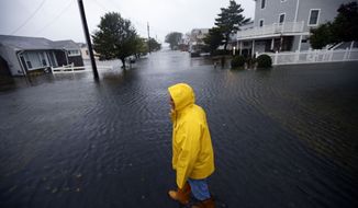 Al Daisey walks in the floodwaters in front of his home in Fenwick Island, Del., on Monday, Oct. 29, 2012, as Hurricane Sandy bears down on the East Coast. (AP Photo/Alex Brandon)