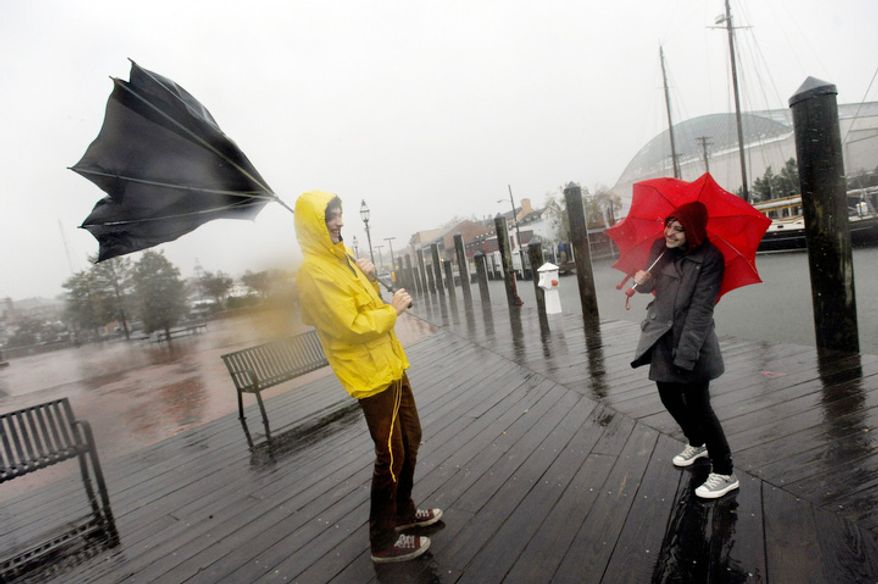 Jake Wilkerson, 20, and Kaityln Baker, 21, both of Annapolis, Md., struggle with their umbrellas as Hurricane Sandy approaches Annapolis Monday, Oct. 29, 2012. (AP Photo/Steve Ruark)