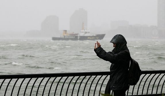 A woman uses her mobile phone to photograph New York Harbor at Battery Park, at the southern tip of Manhattan, Monday, Oct. 29, 2012. Defiant New Yorkers jogged, pushed strollers and took snapshots of churning New York Harbor on Monday, trying to salvage normal routines in a city with no trains, schools and an approaching mammoth storm. (AP Photo/Richard Drew)