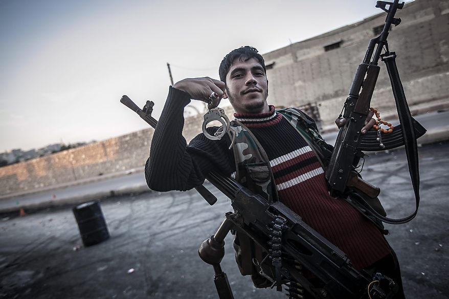A rebel fighter poses for a photo holding handcuffs in the front-line neighborhood of Bustan Al-Pasha in Aleppo, Syria, shortly after an army jet hit the rebel position in the city's northwest. Syria's air force fired missiles and dropped barrel bombs on rebel strongholds while opposition fighters attacked regime positions, flouting a U.N.-backed cease-fire that was supposed to quiet fighting over a long holiday weekend but never took hold. (AP Photo/Narciso Contreras)
