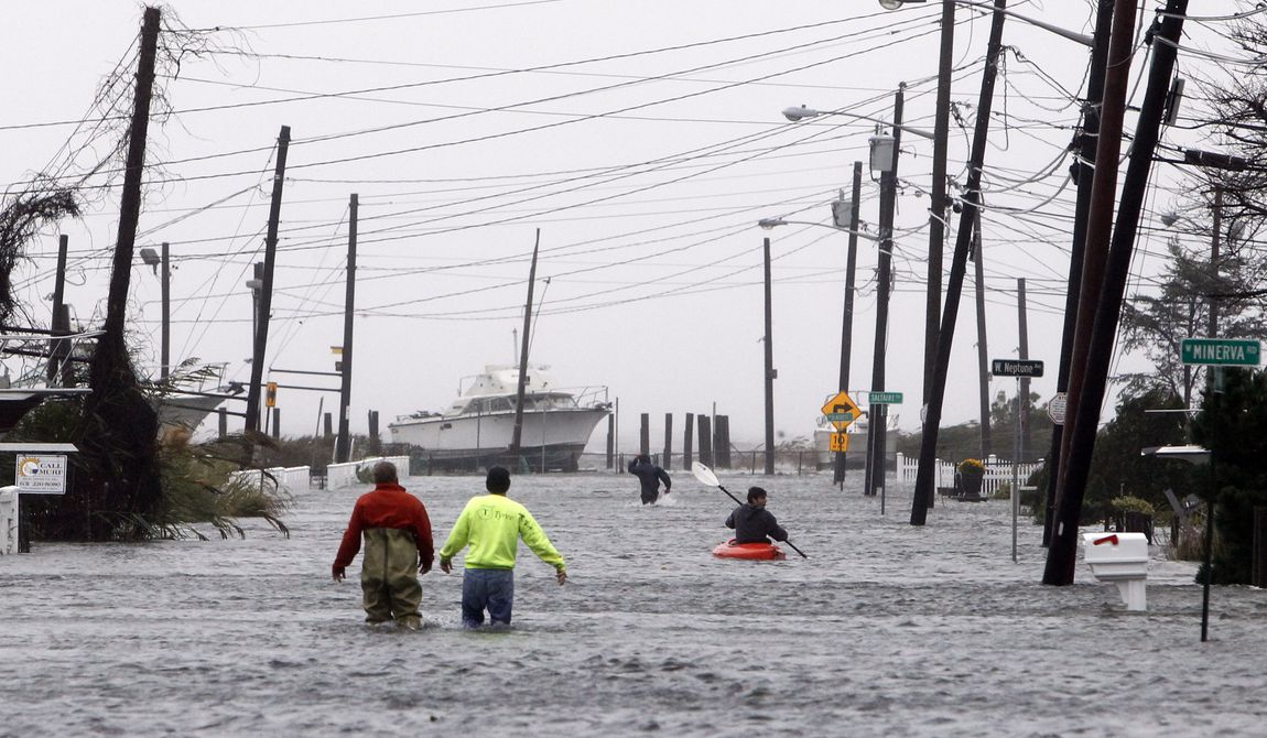 People wade and paddle down a flooded street as Hurricane Sandy approaches, Monday, Oct. 29, 2012, in Lindenhurst, N.Y. (AP Photo/Jason DeCrow)