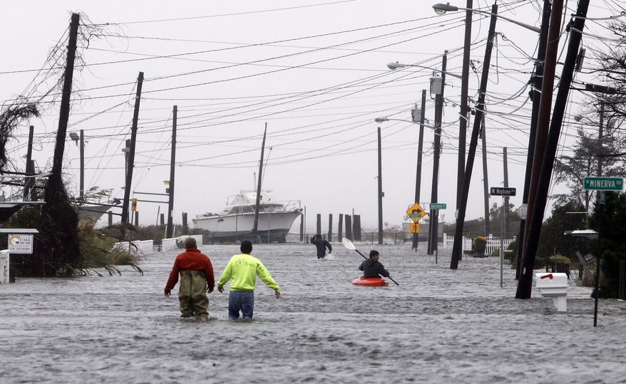 People wade and paddle down a flooded street as Hurricane Sandy approaches, Monday, Oct. 29, 2012, in Lindenhurst, N.Y. (AP Photo/Jason DeCrow)