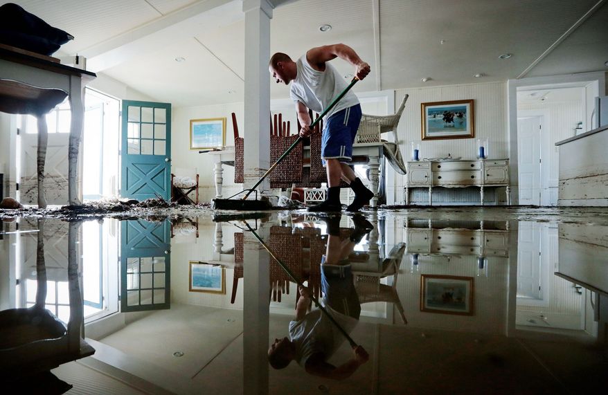 Jason Locke sweeps water and mud from his parents’ home in Westport, Mass., Tuesday, the day after Sandy slammed into the East Coast. With the storm affecting so many oceanfront communities, many homeowners who suffered losses because of flooding likely will find themselves out of luck when it comes to insurance. Standard policies don’t cover flood damage, and the vast majority don’t have specific flood insurance. (Associated Press)
