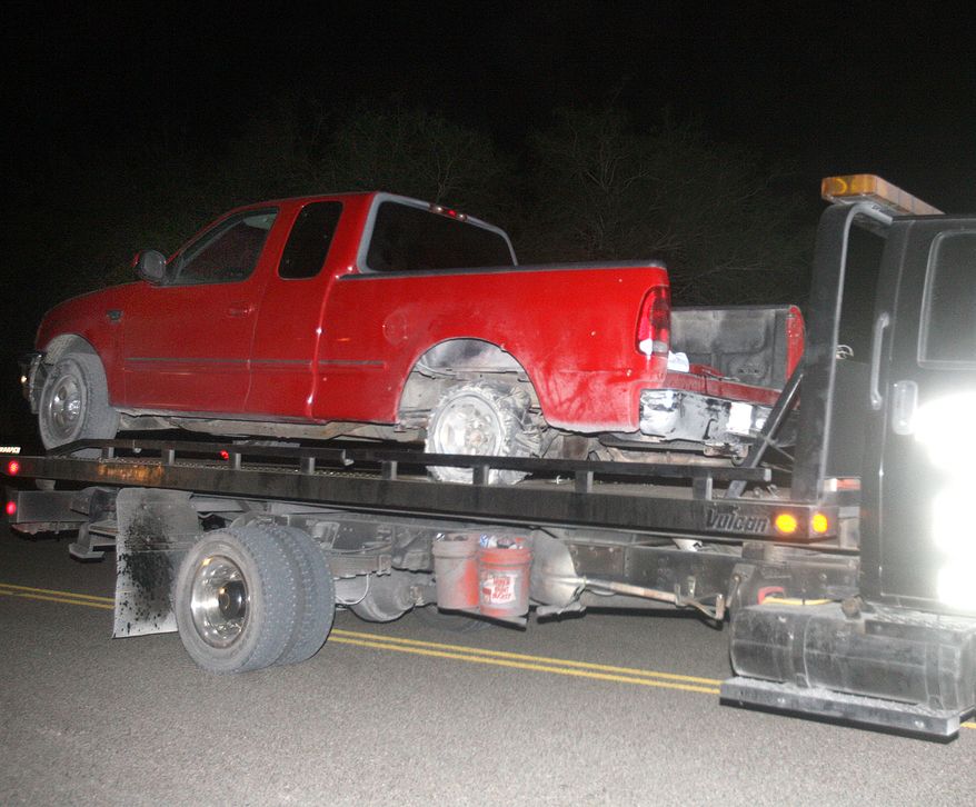 ** FILE ** A red pickup truck is moved from the scene of a incident after a chase between law enforcement and suspected human smugglers north of La Joya, Texas, on Thursday, Oct. 25, 2012. A Texas Department of Public Safety sharpshooter opened fire on an evading vehicle loaded with suspected illegal immigrants, leaving at least two people dead, sources familiar with the investigation said. (AP Photo/The Monitor, Joel Martinez)