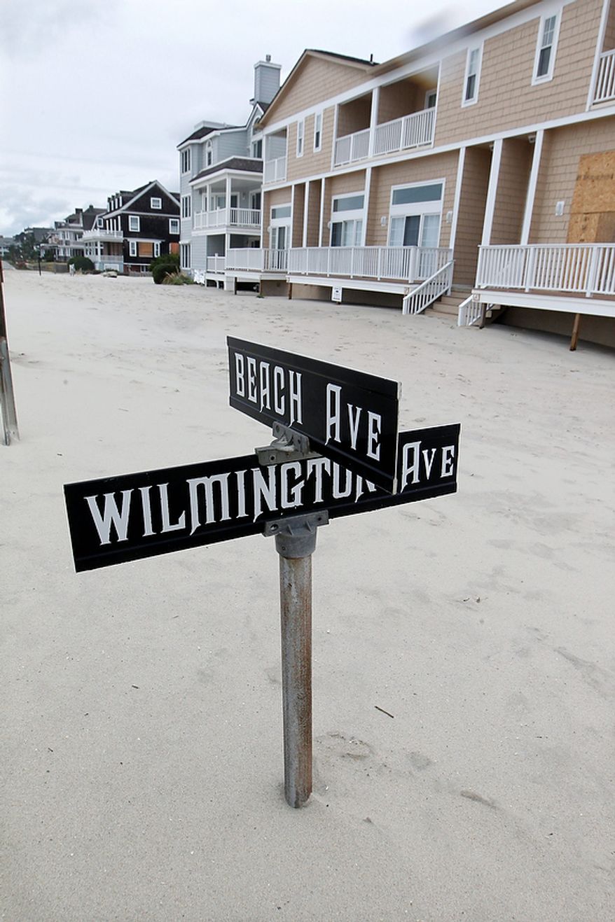 A street sign is partially buried in sand Tuesday morning, Oct. 30, 2012, in Cape May, N.J., after a storm surge from Sandy pushed the Atlantic Ocean over the beach and across Beach Avenue. (AP Photo/Mel Evans)