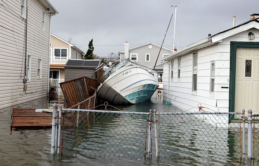 A boat lies toppled between two flooded houses in the aftermath of superstorm Sandy, Tuesday, Oct. 30, 2012, in Lindenhurst, N.Y. (AP Photo/Jason DeCrow)