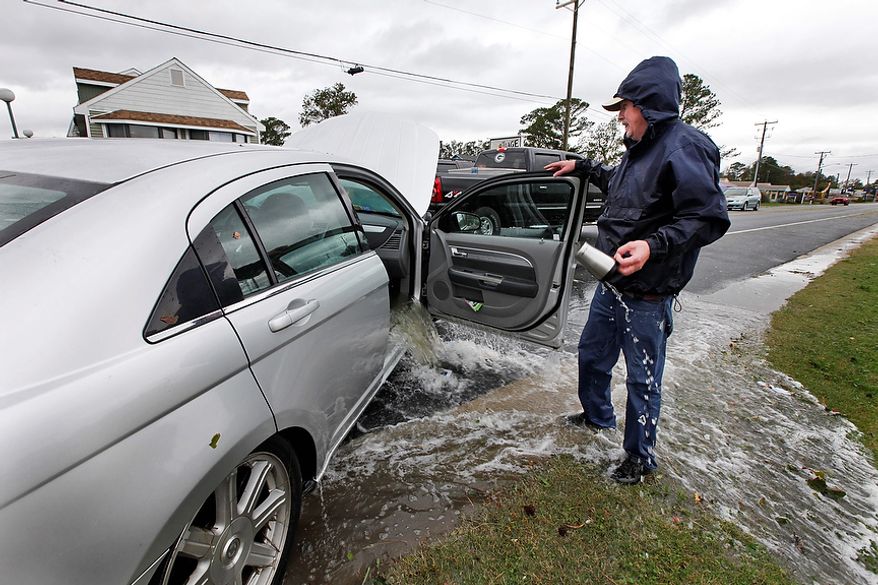 Glenn Heartley watches floodwaters from superstorm Sandy pour out of his car after it was pulled out of a creek in Chincoteague, Va., Tuesday, Oct. 30, 2012. Heartley and his wife were swept off the road into a shallow creek during Monday's storm. (AP Photo/Steve Helber)