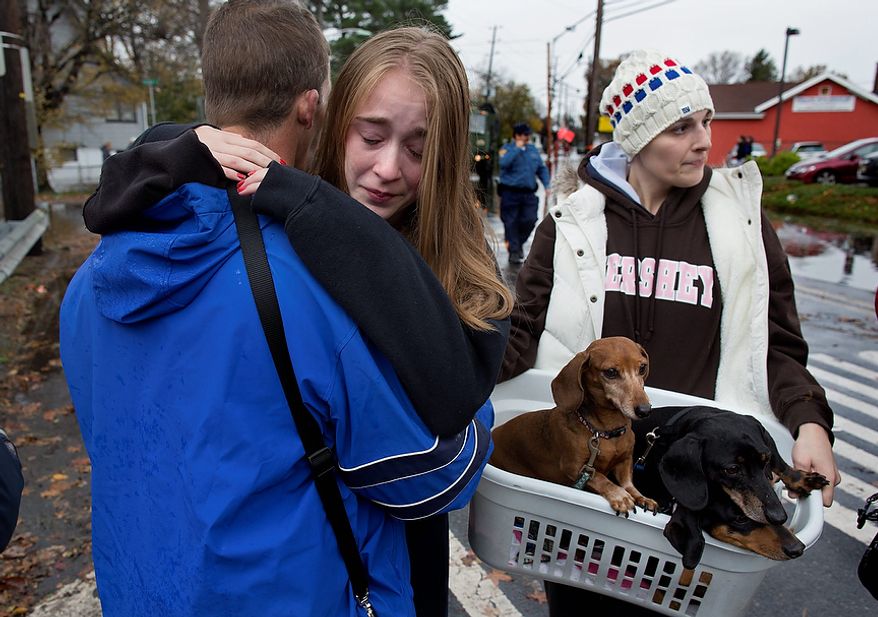 Olivia Loesner, 16, hugs her uncle, Little Ferry Deputy Fire Chief John Ruff, after she was brought from her flooded home in a boat in Little Ferry, N.J., Tuesday, Oct. 30, 2012, in the wake of superstorm Sandy. At right carrying pets, is her mother, Janice Loesner. (AP Photo/Craig Ruttle)