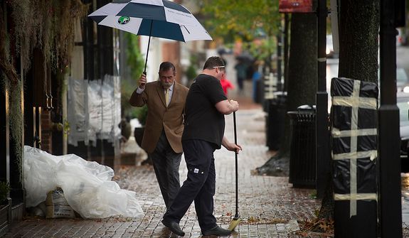 A man passes by and navigates past O&#39;Connell&#39;s Restaurant General Manager Doug Gruenberg (right) as he sweeps small debris from the sidewalk in front of his restaurant as people venture out to survey the damage in Old Town Alexandria, Va., Tuesday, Oct. 30, 2012, the day after Hurricane Sandy slammed into the region. Flood water in Old Town is slightly higher than normal after a heavy rain. (Rod Lamkey Jr./The Washington Times)