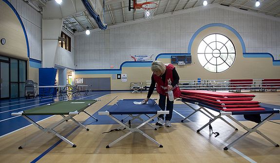 Red Cross volunteer Julie Tarascio wipes down one of the cots in the Lee District REC Center in Alexandria, Va., which served as an animal-friendly shelter for people needing to evacuate their homes due to Hurricane Sandy. They said they had about 23 people stay here Monday night, the youngest of which was 7 weeks old. This image was made Tuesday, Oct. 30, 2012. (Barbara L. Salisbury/The Washington Times)