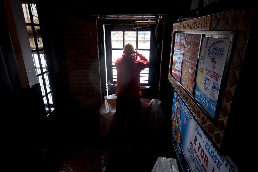 John O'Leary, 41, from Annapolis, Md., looks out of Armadillos restaurant front door at Dock St. which had nearly a foot and half of water, Annapolis, Md., Tuesday, Oct. 30, 2012. The storm left early a foot and half of water along Dock St. but the stores are more worried about the tide which rises at 5:45pm and could bring another two feet of water. (Craig Bisacre/The Washington Times)