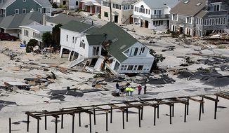 People survey the destruction left in the wake of Superstorm Sandy on Wednesday, Oct. 31, 2012, in Seaside Heights, N.J. (AP Photo/Mike Groll)
