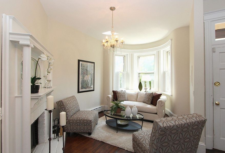 At the front of the home at 718 East Capitol St. NE is a bay-window alcove with tall windows. The alcove faces a wood-burning fireplace that features a detailed white-painted mantel.