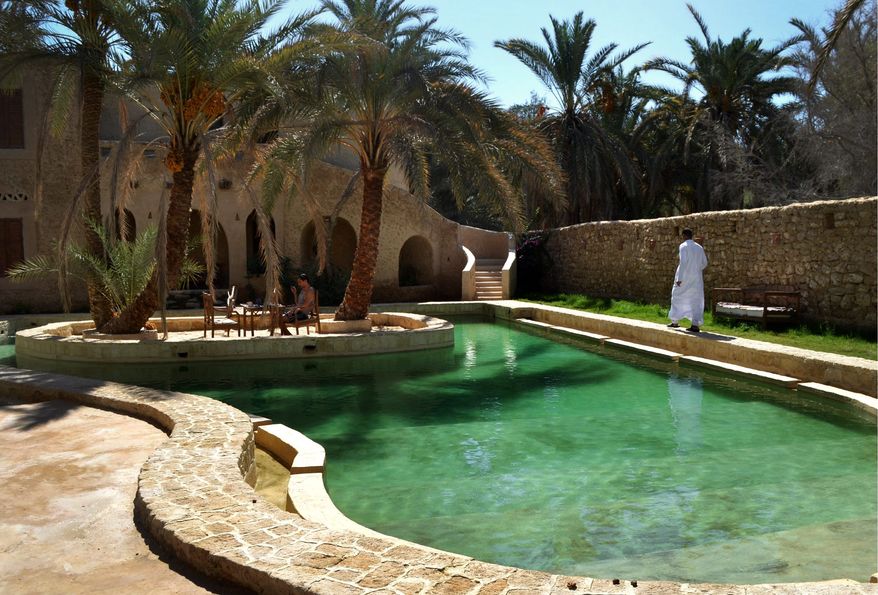 People relax by a freshwater pool at the Ghaliet Ecolodge and Spa in the Egyptian oasis of Siwa, a Berber town of some 27,000 people roughly 450 miles southwest of Cairo. The palm tree-lined area is known for its quiet charm, ancient ruins, abundant natural springs and rolling sand dunes in the surrounding desert. (AP Photo/Kim Gamel)