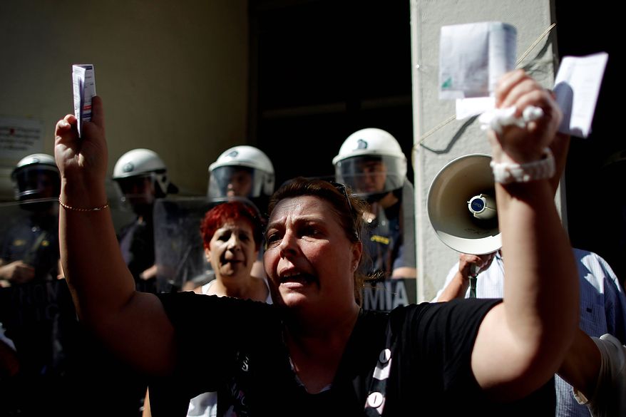 In this Sept. 28, 2012 file photo, private hospital nurse Paraskevi Petropoulou holds up her unpaid electricity and income tax bills during a protest outside the Health Ministry in central Athens. Petropoulou said that she has not been paid for more than five months, because the government owes money to private hospitals who in turn are unable to pay their employees. To the casual visitor, all might appear well in Athens, but scratch the surface and you find a society in freefall, ripped apart by the most vicious financial crisis the country has seen in half a century. (AP Photo/Petros Giannakouris, File)