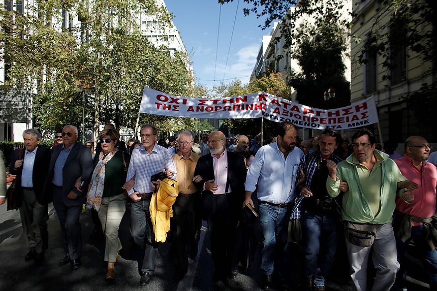 Journalists march in central Athens during a protest, Wednesday, Oct. 31 2012. The banner reads "Don't Ax Human Dignity". Greece's two main labor unions covering civil servants and the private sector have called a 48-hour strike to protest austerity measures due to be voted on next week. The strike call came as the finance minister submitted an amended 2013 budget that raised the country's debt and deficit forecasts for next year. (AP Photo/Kostas Tsironis)