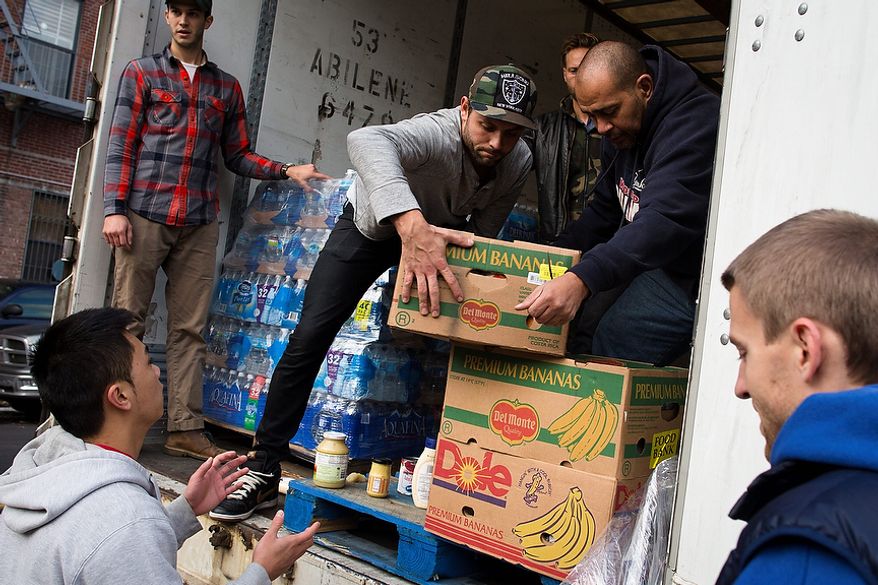 Volunteers help unload food from a truck for distribution to the residents of the Lower East Side who remain without power due to Superstorm Sandy, Friday, Nov. 2, 2012, in New York. In Manhattan, where 226,000 buildings, homes and business remain without power, Consolidated Edison says they should have service restored by Saturday. (AP Photo/ John Minchillo)