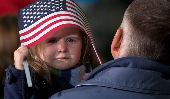 A little girl takes shelter under and American Flag before President Barack Obama arrives to speak at a campaign event at the Franklin County Fairgrounds, Friday, Nov. 2, 2012, in Hilliard, Ohio, before heading to another campaign stop in in Springfield, Ohio. (AP Photo/Carolyn Kaster)