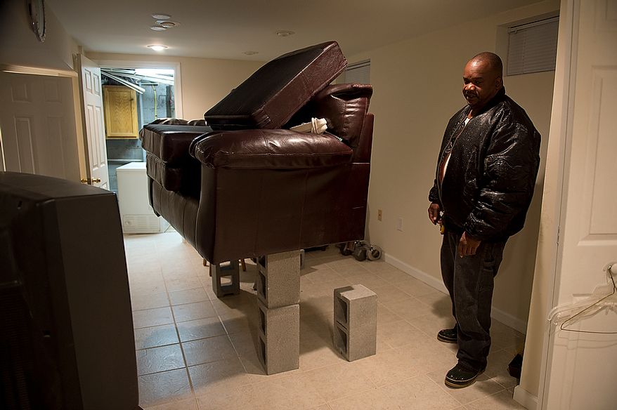 Kevin Dorsey, who has lived in his Huntington, Va. home for 13 years, has his basement furniture up on cinder blocks and says he realizes it still might float off of them. He has taken precautions to try to prevent water from coming into his basement, including boarding up the windows and sealing them with silicone and rubber tape, but he says it will likely still seep through. His neighbor has a generator that he can tie into, so he might stay at home if his local relatives lose power too. This image was made Monday, Oct. 29, 2012. (Barbara L. Salisbury/The Washington Times)