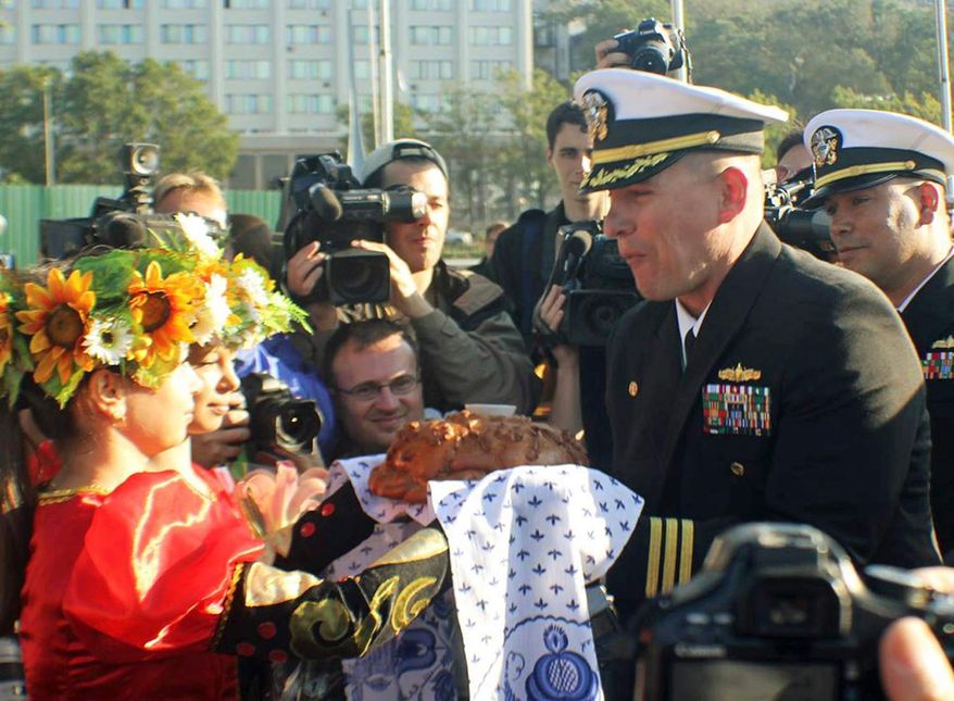 ** FILE ** In this Sept. 20, 2012, photo made available by the U.S. Navy, Cmdr. Joseph R. Darlak, right foreground, commanding officer of the guided missile frigate USS Vandegrift, takes a bite of a traditional offering of bread and salt after arriving in Vladivostok for a port visit during operations in the Western Pacific. Cmdr. Darlak was relieved of command Friday, Nov. 2, 2012, in San Diego, after an investigation for demonstrating poor leadership and failing to ensure proper officer conduct during the three-day September stop. (AP Photo/U.S. Navy Photo by Lt. J.G. Ryan P. Mutha)
