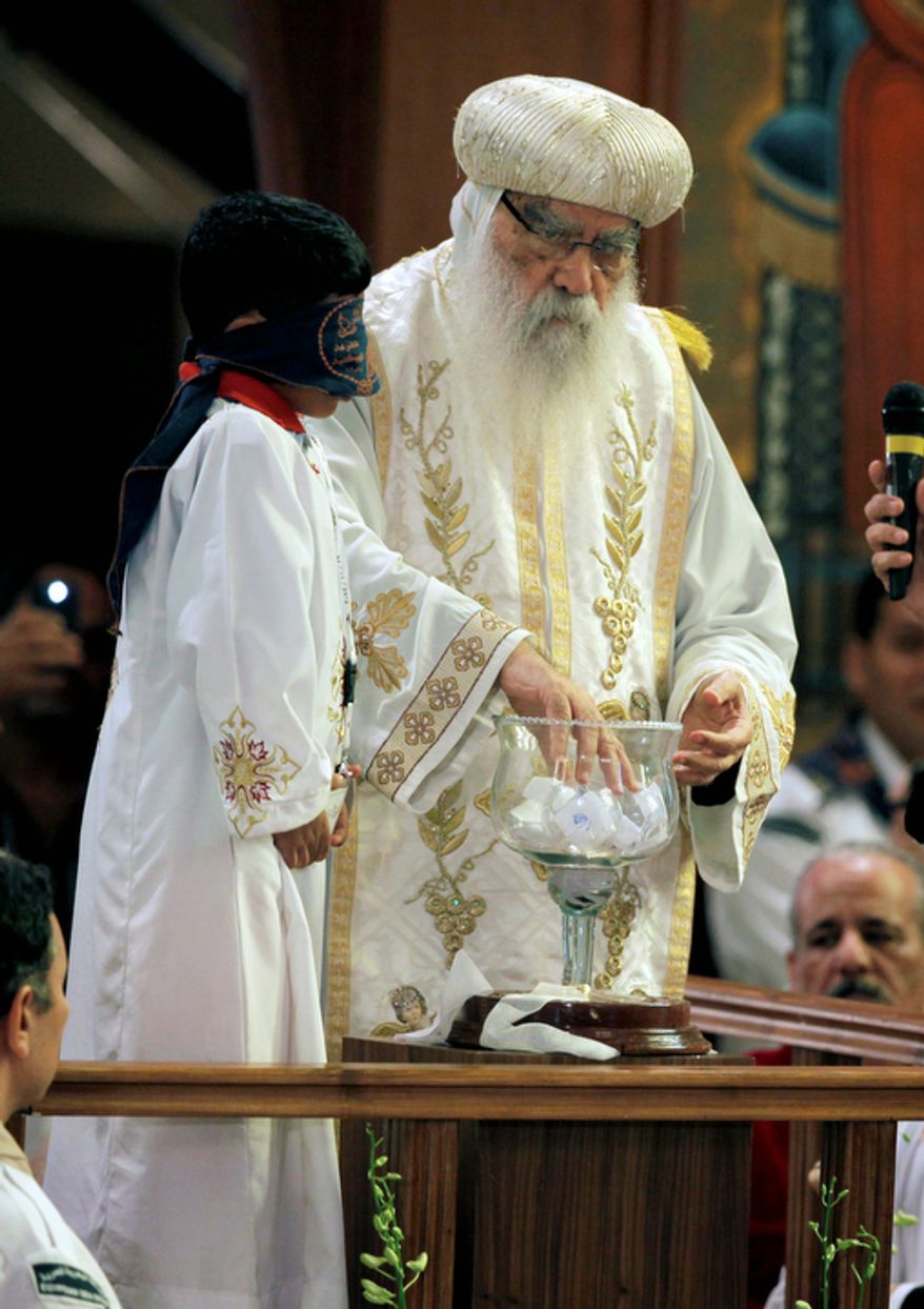 A blindfolded boy waits to draw the name of the next patriarch from a crystal chalice while acting Coptic Pope Pachomios mixes the balls with the candidates names during the papal election ceremony at the Coptic Cathedral in Cairo, Egypt, Sunday, Nov. 4, 2012. Bishop Tawadros will be ordained Nov. 18 as Pope Tawadros II. (AP Photo/Nasser Nasser)