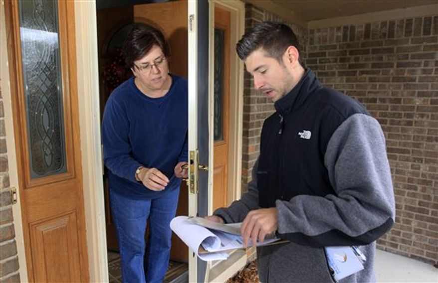 In a photo from Thursday, Nov. 1, 2012, David Herbeck prepares to give Katherine Davenport some campaign literature as he walks door-to-door in a Livonia, Mich., suburb reminding voters to vote on Tuesday. (AP Photo/Carlos Osorio)