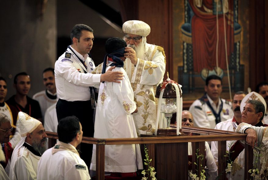Acting Coptic Pope Pachomios (center) blindfolds the boy elected to draw the name of the next patriarch from a crystal chalice during an elaborate papal election ceremony at the Coptic cathedral in Cairo on Sunday, Nov. 4, 2012. (AP Photo/Nasser Nasser)