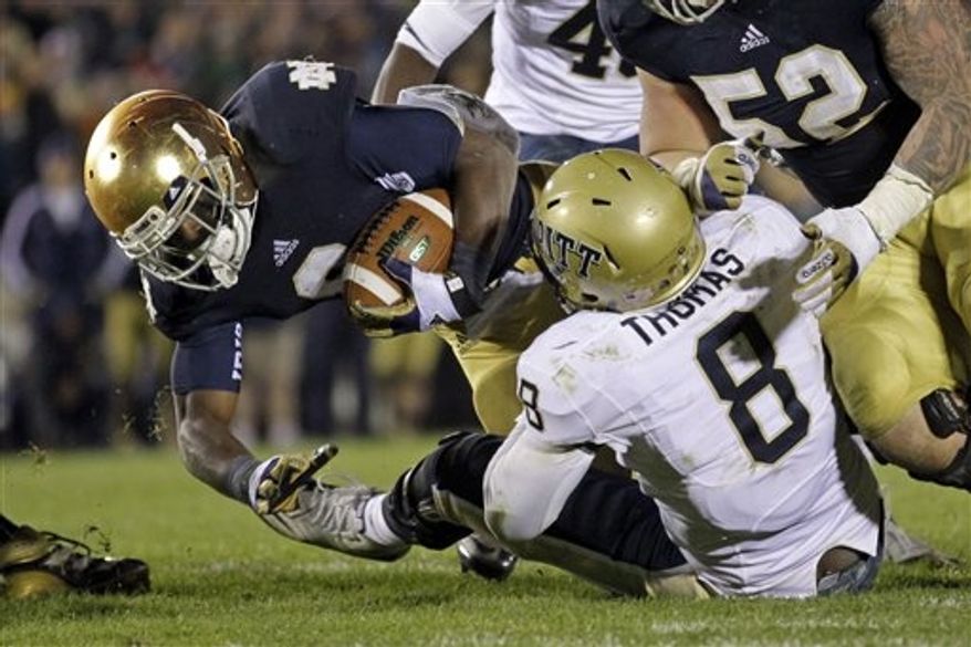 Notre Dame running back Theo Riddick drives to the one-yard line as he is tackled by Pittsburgh linebacker Todd Thomas during the third overtime period in an NCAA college football game in South Bend, Ind., Saturday, Nov. 3, 2012. Notre Dame defeated Pittsburgh 29-26 in triple overtime. (AP Photo/Michael Conroy)