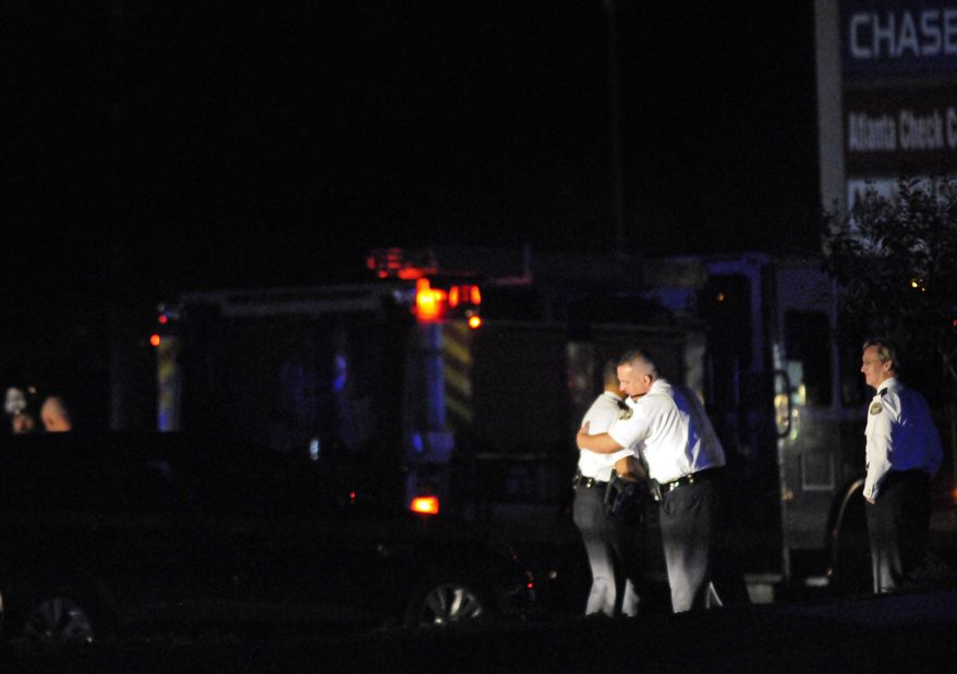 **FILE** Law enforcement officers console each other Nov. 4, 2012, as others investigate the scene of an Atlanta Police Department helicopter crash that killed two officers aboard the chopper when it crashed near a shopping center late Saturday, Nov. 3, 2012. (Associated Press)