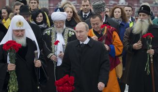 Russian President Vladimir Putin (center) walks with religious leaders of various denominations at Red Square in Moscow as they go to place flowers at a statue of Minin and Pozharsky, the leaders of a struggle against foreign invaders in 1612, to mark the National Unity Day on Sunday, Nov. 4, 2012. (AP Photo/Misha Japaridze)