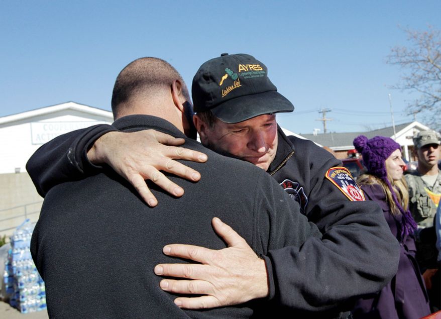 New York Fire Department Marine Ops Batallion Chief James Dalton, right, who is in charge of "dewatering," embraces a colleague after losing his composure while giving instructions to dozens of New York Cares volunteers who came to the area for the day to help in Breezy Point, in the wake of Superstorm Sandy, Sunday, Nov. 4, 2012, in New York. (AP Photo/Kathy Willens)